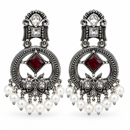 Handcrafted oxidised owl-inspired chandbali earrings with ruby-maroon crystal stone, sparkling AD stones, and elegant pearl hangings.